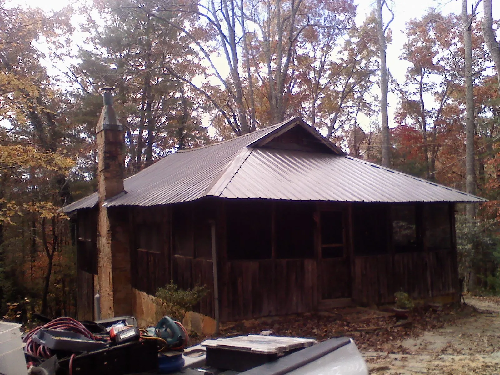 Brown metal hip roof on an old cabin with a stone chimney in Gonvick