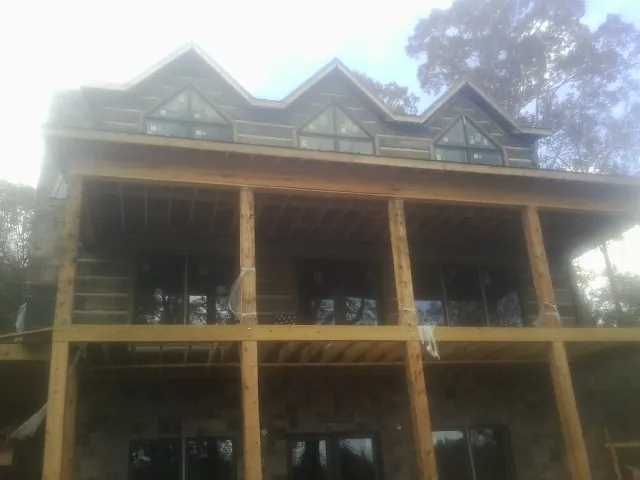 Dormers and porch framing on a large log home under construction — Roof Coating work by our crew in Gonvick