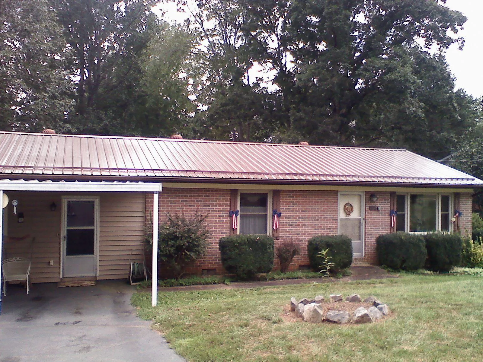 Bronze metal roof and carport on a brick ranch home — Roof Repair work by our crew in Gonvick