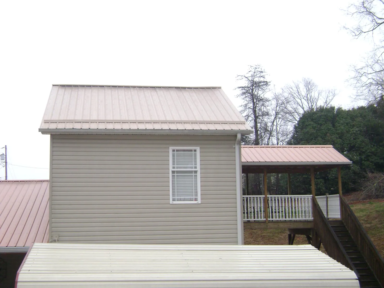 Tan metal roofs on a two story addition and attached porch, from a Roof Replacement job in Gonvick